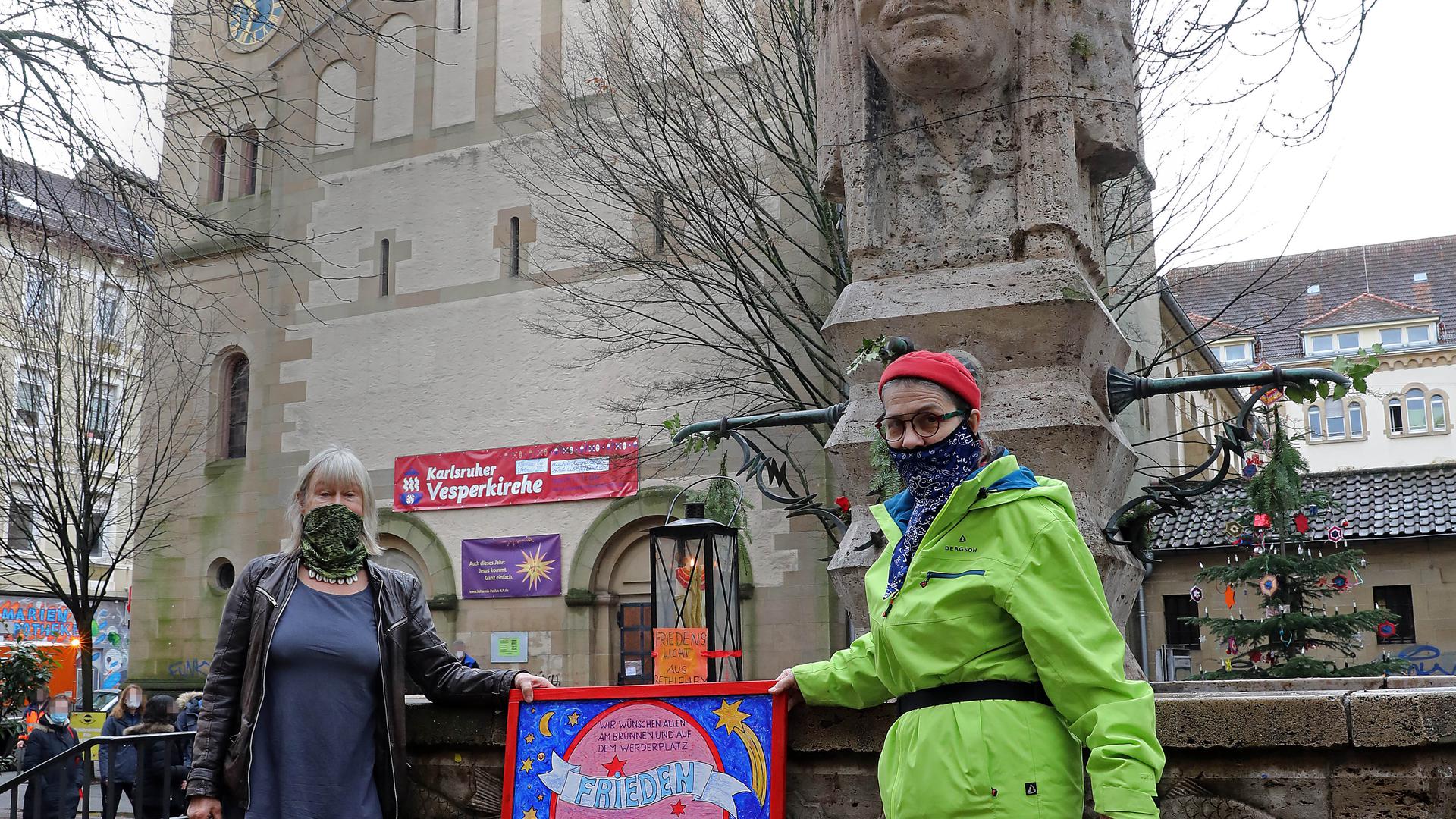 Symbol der Hoffnung: Pfarrerin Lara Pflaumbaum (rechts) und Künstlerin Gudrun Roth brachten das Friedenslicht an den Indianerbrunnen. 