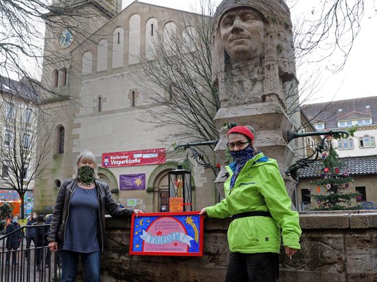 Symbol der Hoffnung: Pfarrerin Lara Pflaumbaum (rechts) und Künstlerin Gudrun Roth brachten das Friedenslicht an den Indianerbrunnen. 