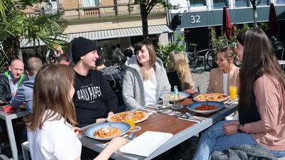 T-Shirt und Wollmütze: Am Ludwigsplatz lassen Mira, Markus, Melanie, Lisa und Laura (von links) die Woche kulinarisch ausklingen. In der Sonne ist es spätsommerlich angenehm, im Schatten herbstlich kühl.