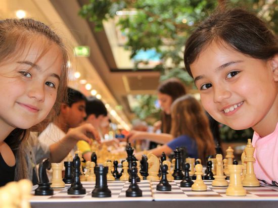 Zwei kleine Mädchen spielen Schach.