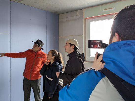 BNN-Videoredakteur Lucas Pflaum lässt sich von drei Mitgliedern der „Nest Generation“ bei einer Hausführung die Fortschritte im Rohbau zeigen.