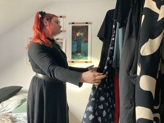 Frau schaut sich Kleider auf einer Kleiderstange an.