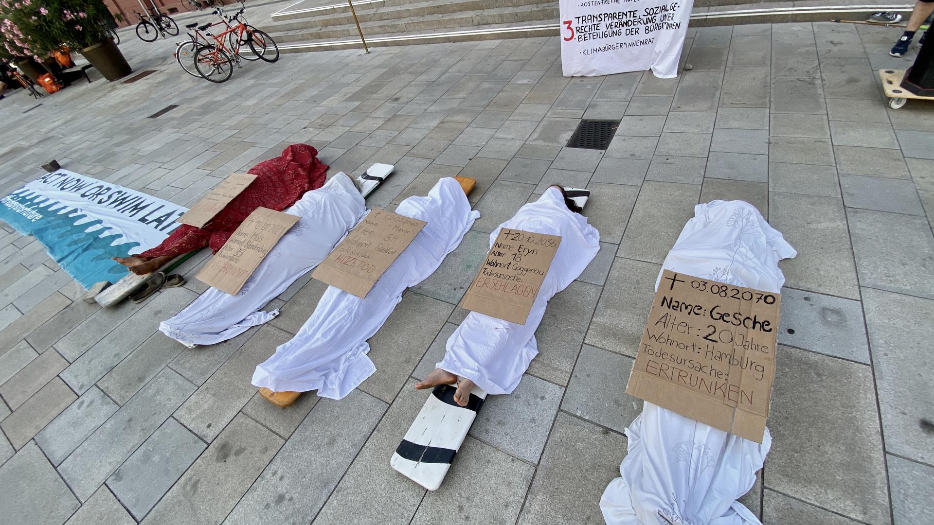 „Hitzetod“, „Ertrunken“: Mit einem „Die-in“ haben Karlsruher Klimaaktivisten vor dem Rathaus auf die drastischen Folgen des Klimawandels aufmerksam gemacht. 