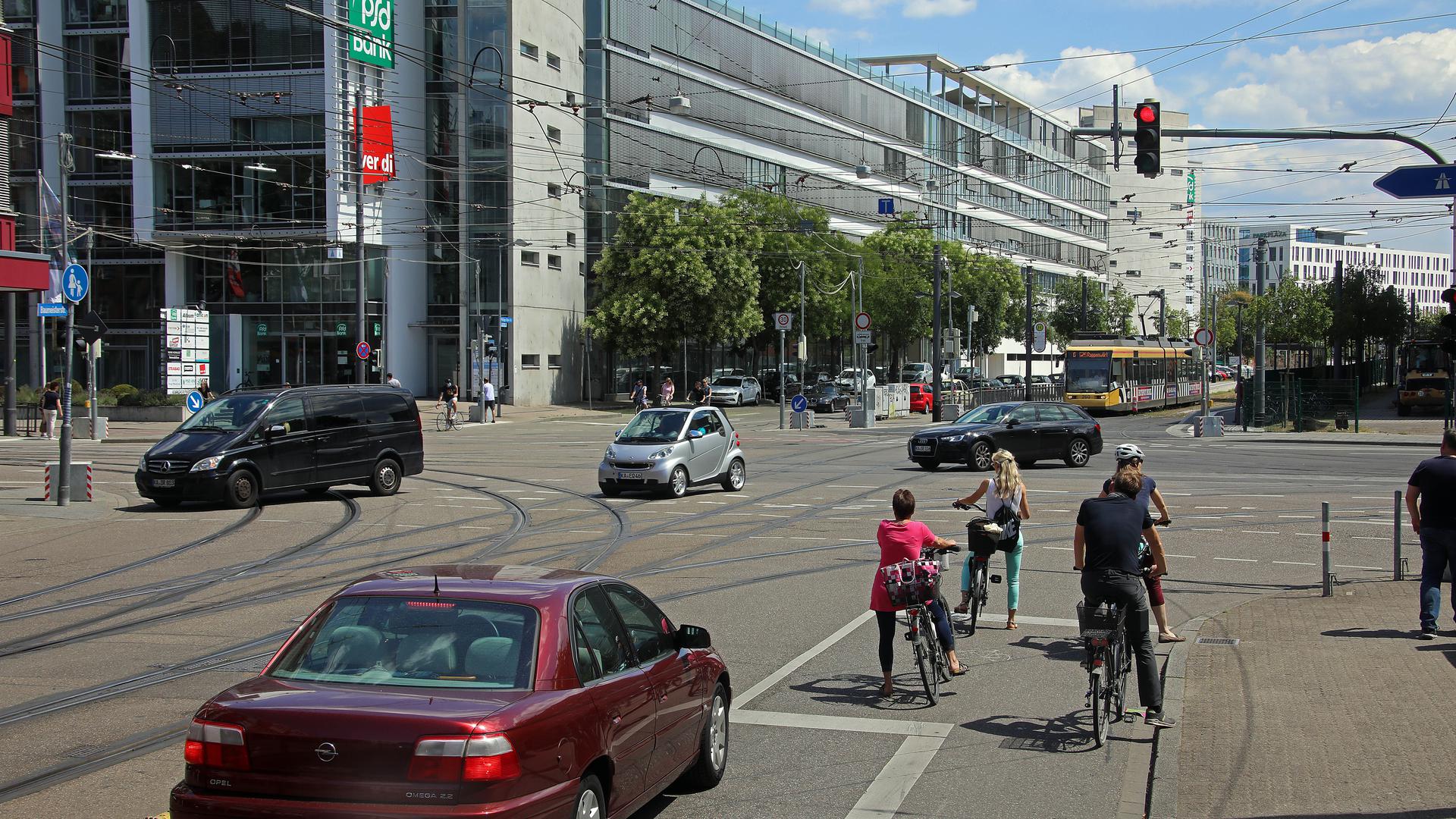 Blick auf die Einmündung der Baumeisterstraße in die Rüppurrer Straße am Rüppurrer Tor mit wartenden Radfahrern inmitten von Autos und einer Straßenbahn im Hintergrund.
