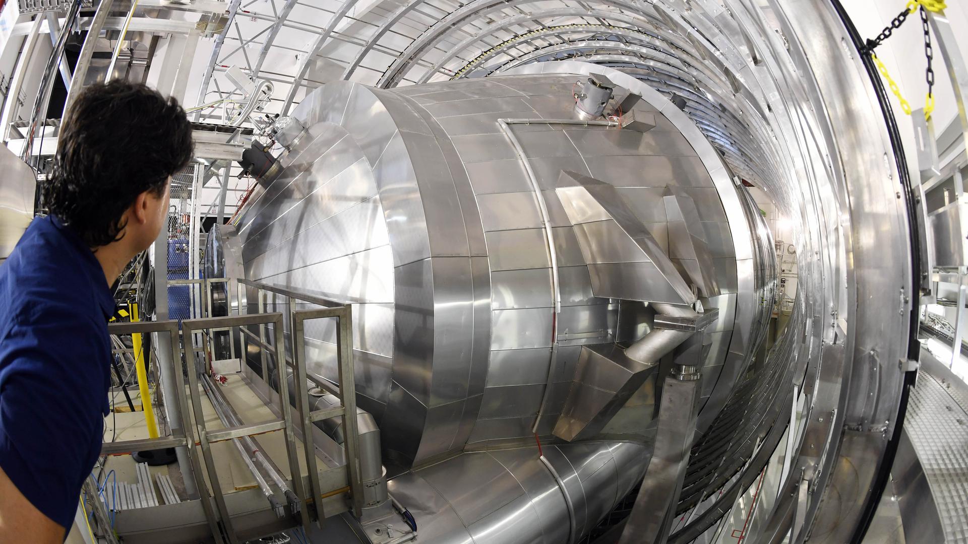 Ein Mitarbeiter des Karlsruher Tritium Neutrino Experiments (Katrin) am Karlsruher Institut für Technologie (KIT) blickt auf das Hauptspektrometer der Anlage.