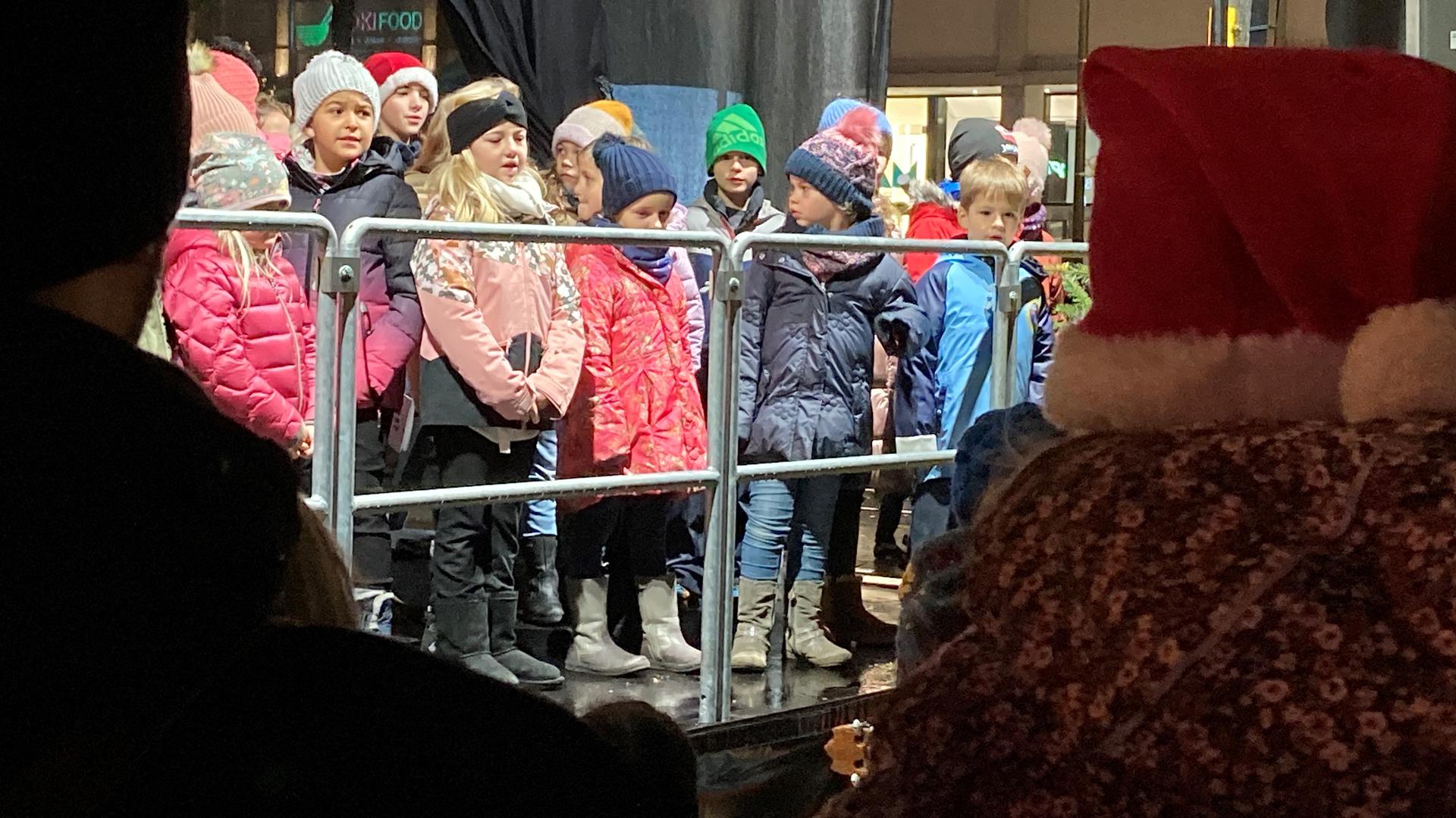 Kindersingen auf dem Weihnachtsmarkt in Karlsruhe: Nahaufnahme der jungen Sänger in Winterkleidung.