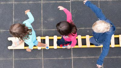 Kinder balancieren auf einer Leiter in einer Kita