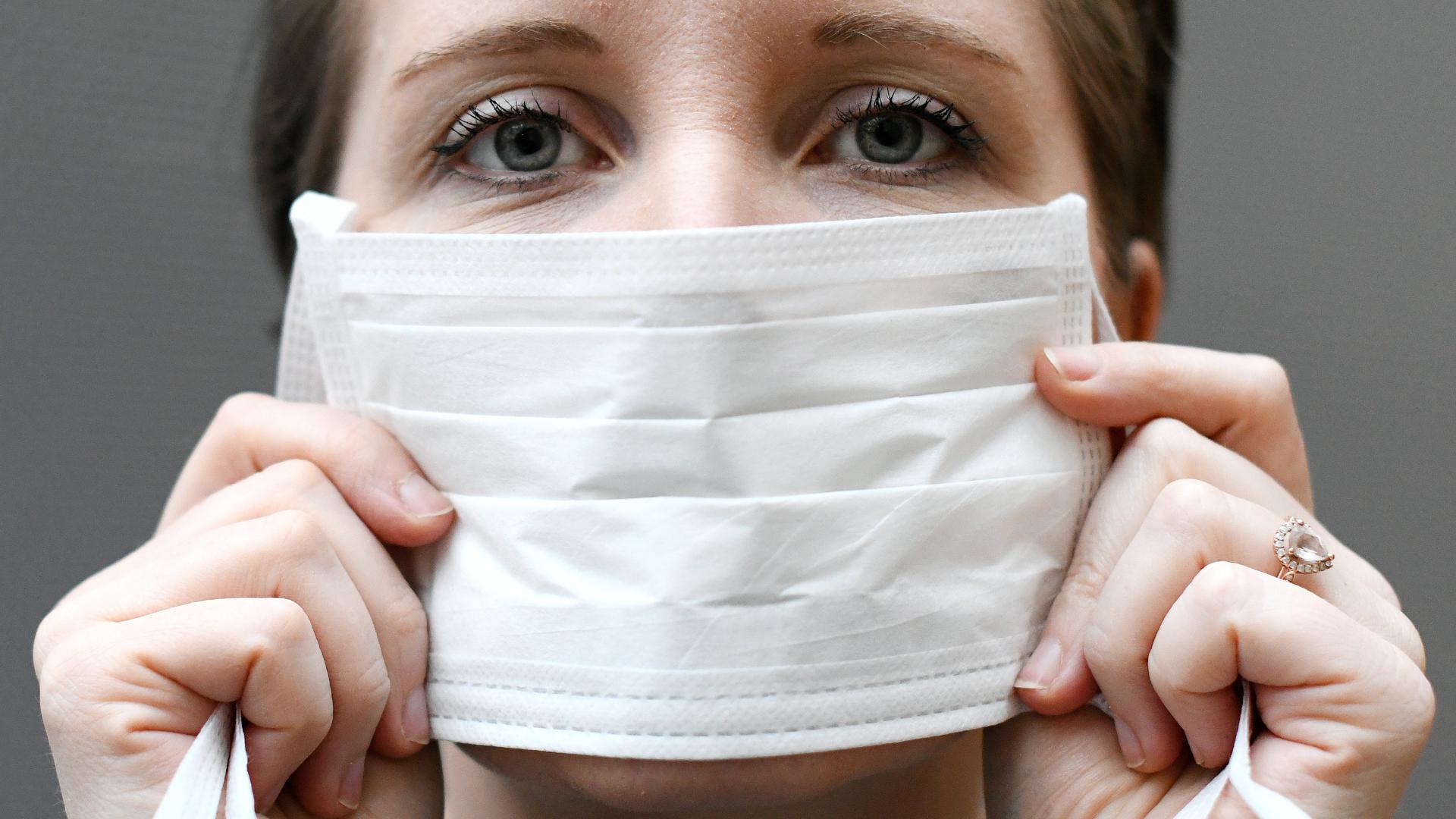 Eine Frau hält einen Mundschutz vor ihrem Gesicht. 