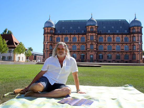 Schauburg-Chef Herbert Born sitzt vom dem Schloss Gottesaue auf einer Picknick-Decke.