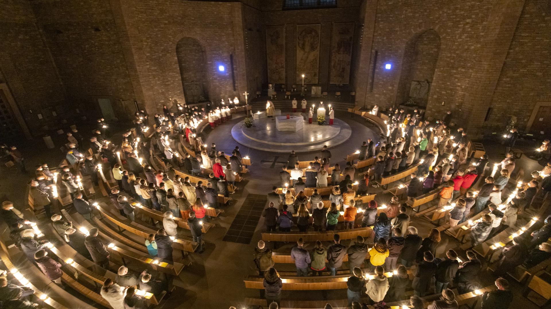 Gut gefüllt: Die Kirche St. Stephan wird zu Beginn des Ostergottesdienstes am Karsamstag durch Kerzenlicht erhellt.