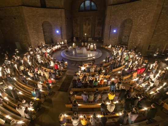 Gut gefüllt: Die Kirche St. Stephan wird zu Beginn des Ostergottesdienstes am Karsamstag durch Kerzenlicht erhellt.