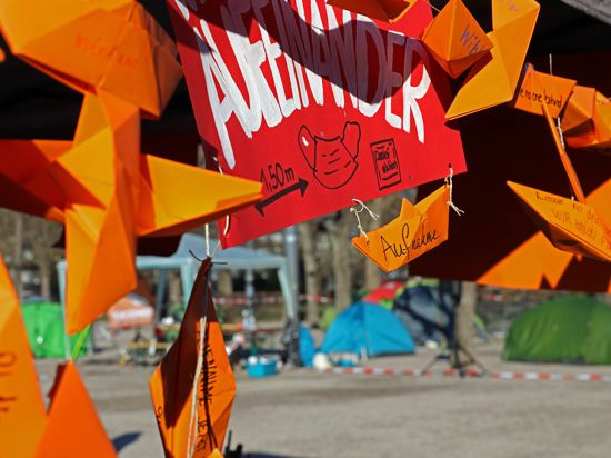Orangene Papierboote im Vordergrund, Zelte im Hintergrund