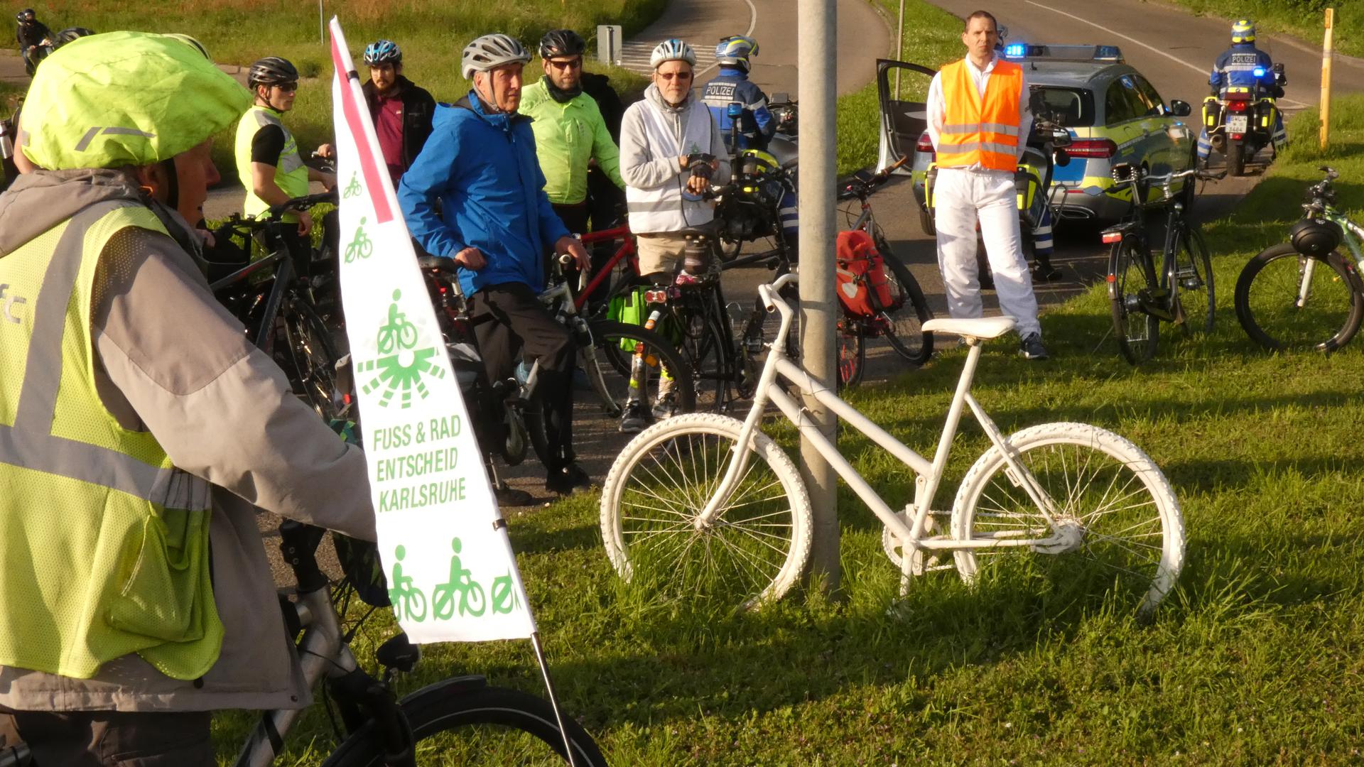 Die Teilnehmer der Demonstrationsfahrt stehen an einem Ghost Bike.