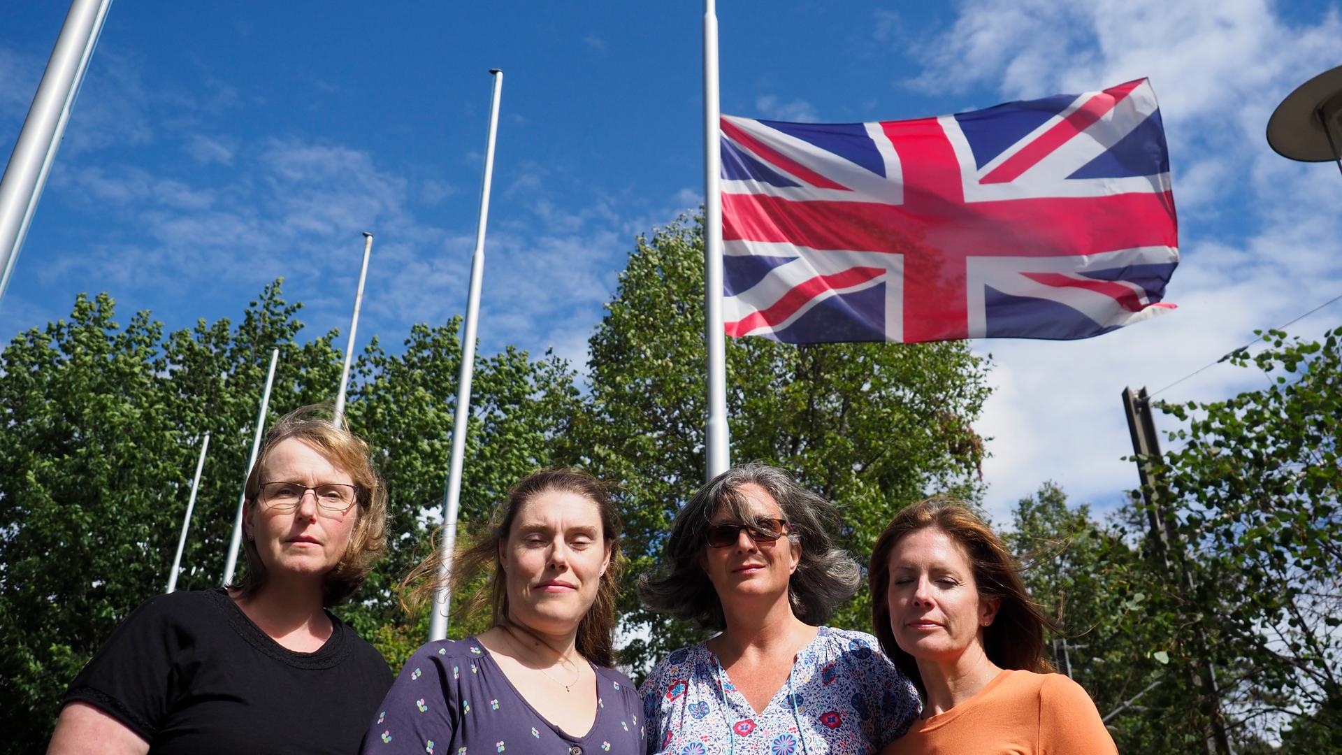 Becky Johnson, Rachel Weller, Catriona McLean und Joanne Molloy nehmen Anteil am Tod der Queen vor der auf Halbmast stehenden britischen Fahne bei der Europaschule in Karlsruhe