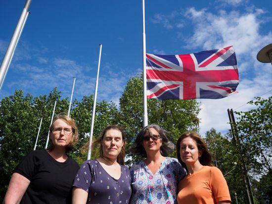 Becky Johnson, Rachel Weller, Catriona McLean und Joanne Molloy nehmen Anteil am Tod der Queen vor der auf Halbmast stehenden britischen Fahne bei der Europaschule in Karlsruhe