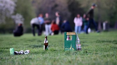 Flaschen stehen auf der Wiese im Schlossgarten, dahinter unscharf Menschen