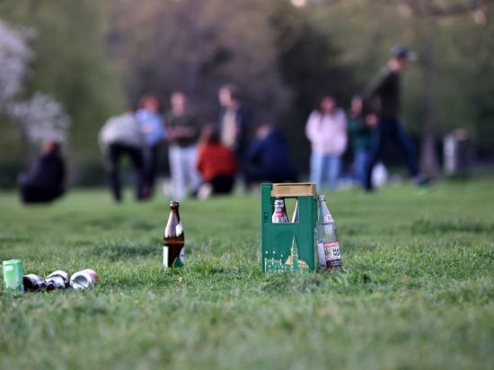 Flaschen stehen auf der Wiese im Schlossgarten, dahinter unscharf Menschen