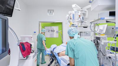 Zwei Klinikmitarbeiter schieben einen Patienten in den Operationssaal.