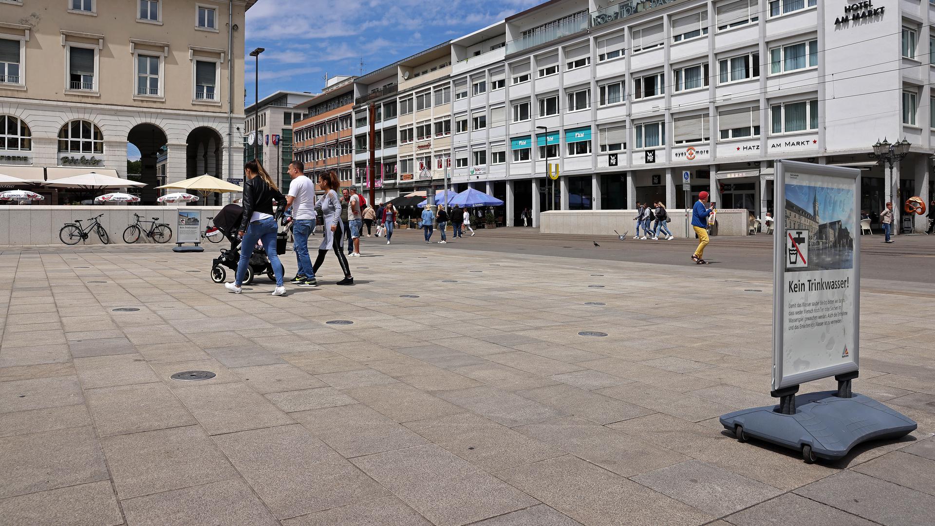 Menschen laufen über das Fontänenfeld der Wasserspiele auf dem Karlsruher Marktplatz