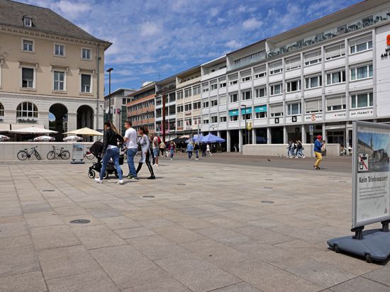 Menschen laufen über das Fontänenfeld der Wasserspiele auf dem Karlsruher Marktplatz