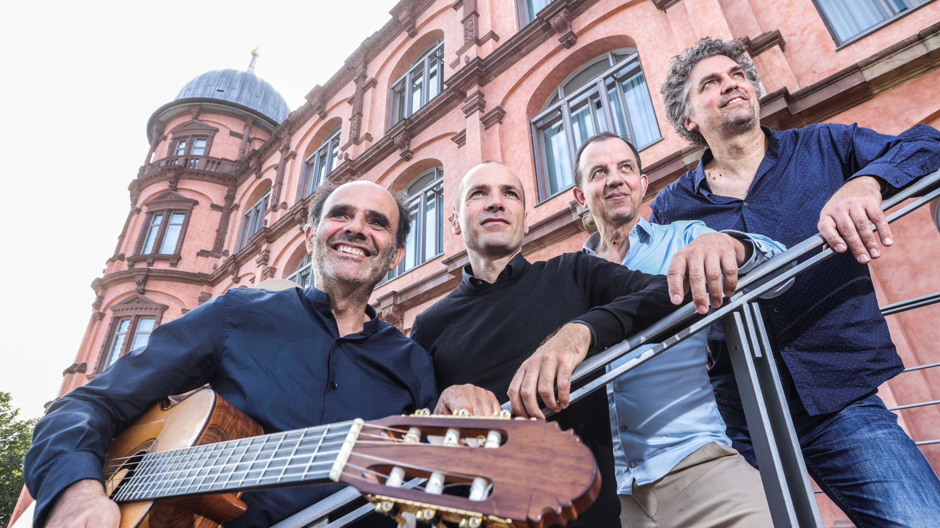 Das Aleph-Quartett mit Andrés Hernández Alba, Christian Wernicke, Wolfgang Sehringer und Tillmann Reinbeck (von links) steht vor dem Schloss Gottesaue in Karlsruhe an einem Treppengeländer mit einer Gitarre.