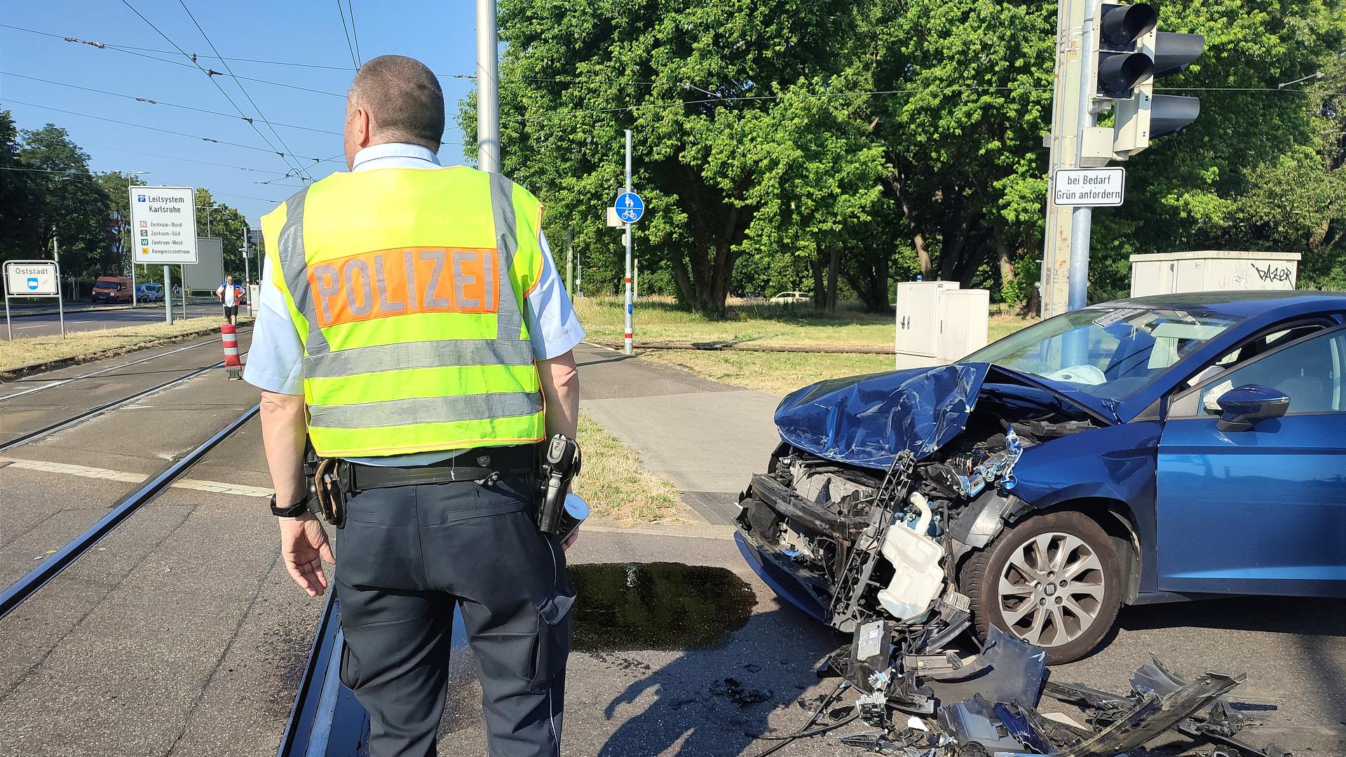 Ein Polizist steht neben einem beschädigten Auto.