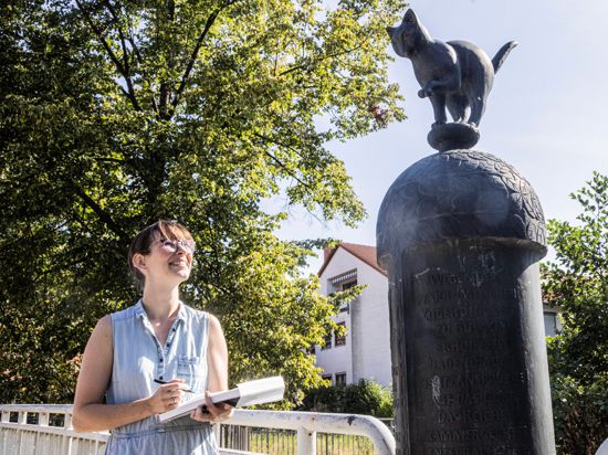 Eine Frau zeichnet auf der Albbrücke, die Beiertheim mit Bulach verbindet, eine Katzenskulptur.