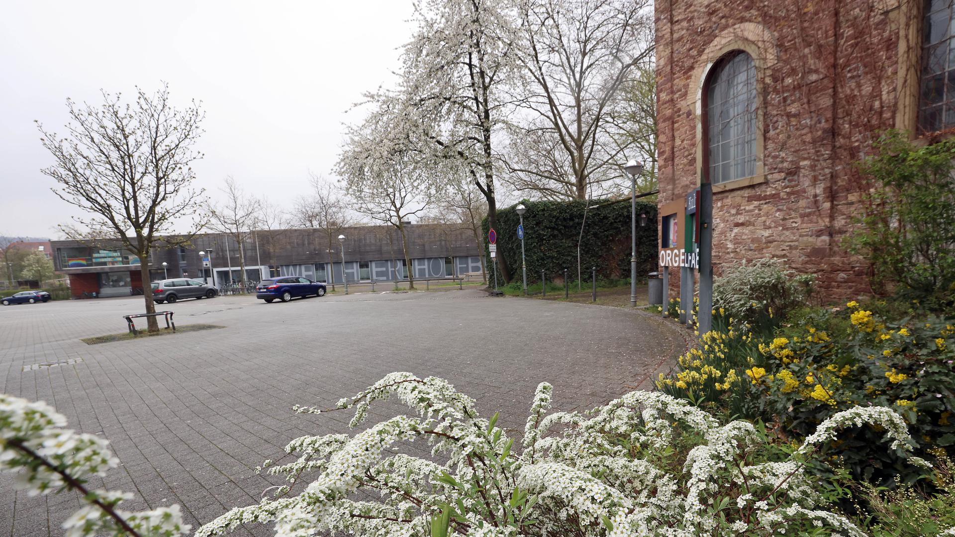 Im April 2022 ist der Weiherhof in Durlach im wesentlichen grau. Dass Autos zwischen der Orgelfabrik (rechts) und dem Weiherhofbad (hinten) parken dürfen, gilt als Notlösung.