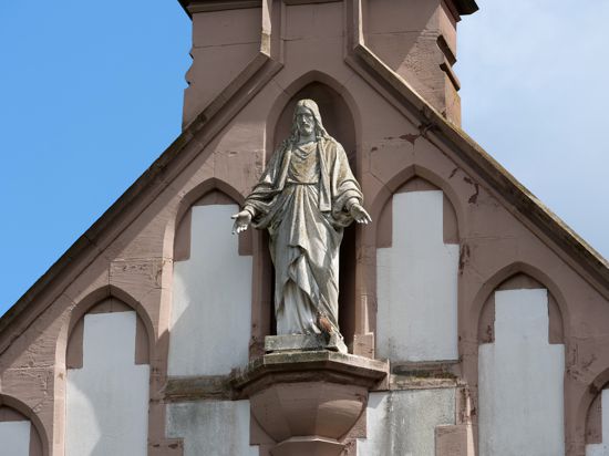 Turmfalke am Fuß der Jesus Skulptur an der Fassade der Kapelle des Bergfriedhofs Durlach