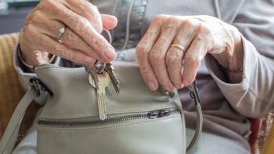 Seniorin holt Schlüssel aus einer Handtasche