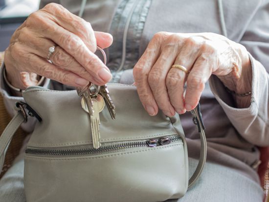 Seniorin holt Schlüssel aus einer Handtasche