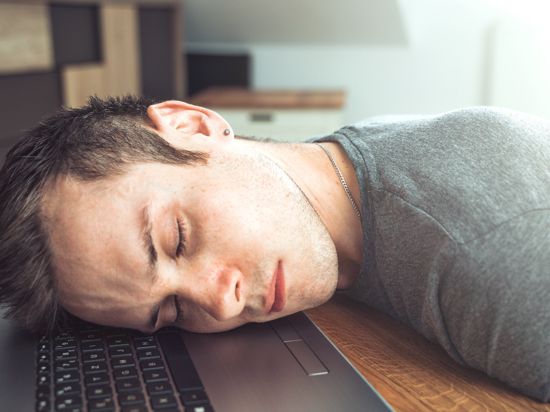 Bavaria, Germany - 18 May 2021: tired man sleeps on his notebook at work in home office - he lies with head on keyboard 