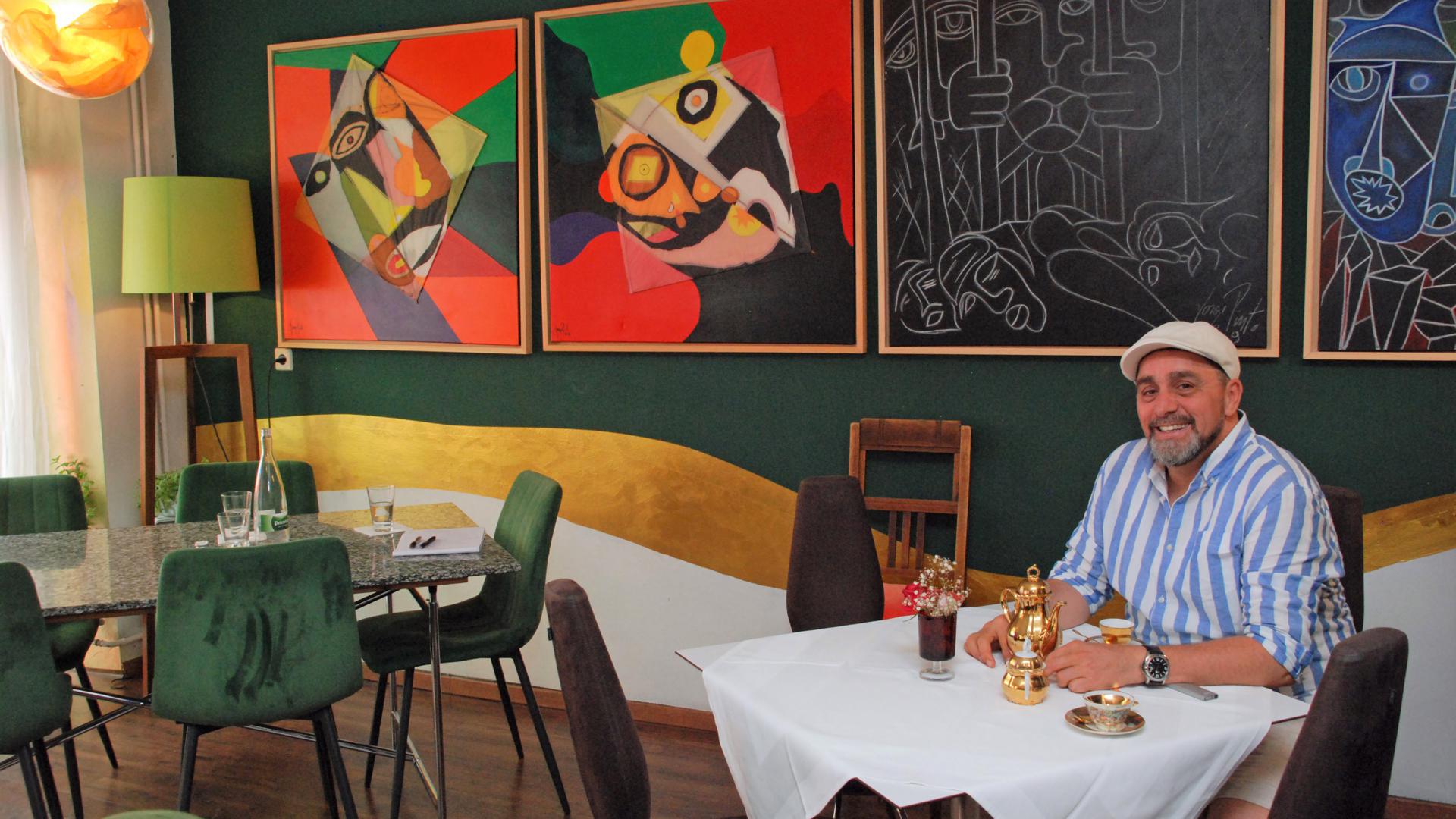 Jorge Sotomayor sitzt in seinem „Cilantro“ unter großformatigen Gemälden.