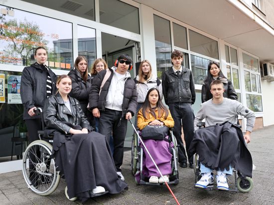 Zehn junge Erwachsene, davon drei im Rollstuhl und einer mit Blindenstock, stehen vor der Adresse der Reha Südwest am Waldhornplatz in der östlichen Karlsruher City.