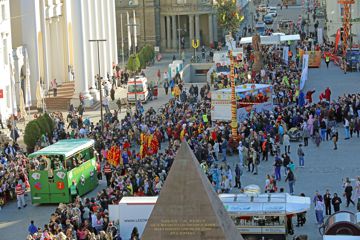 Fastnachtswagen schieben sich durch Zuschauer zwischen der Pyramide auf dem Karlsruher Marktplatz und der evangelischen Stadtkirche.