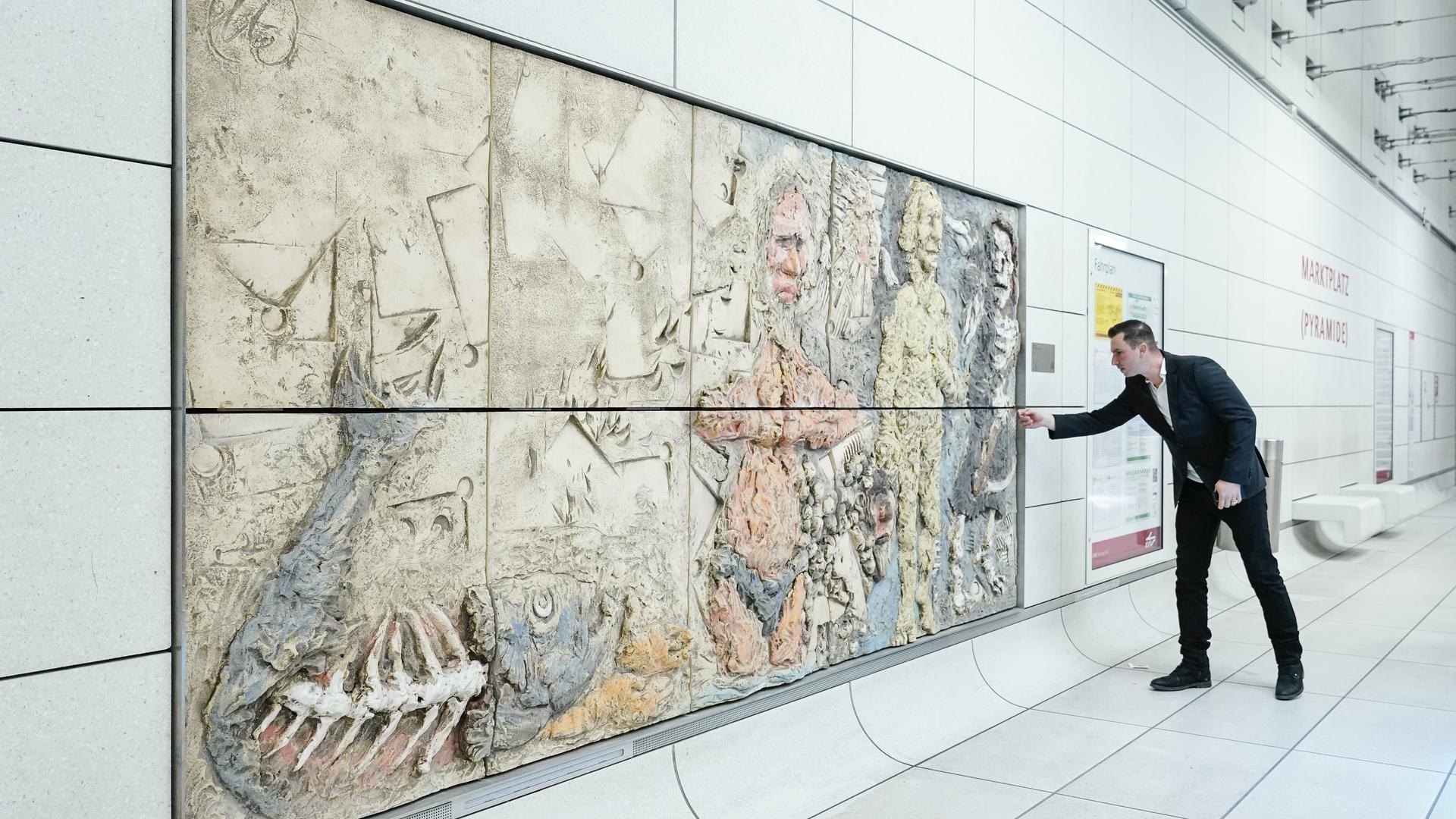 Ein Besucher der Vernissage betrachtet bei der Enthüllung der Lüpertz-Kunstwerke zum Thema „Genesis“ das Kunstwerk mit dem Titel „Die Locken einer Frau“ in der Karlsruher U-Bahn. 