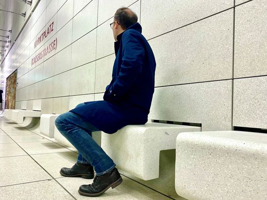 Ein Mann sitzt an der Karlsruher U-Bahn-Haltestelle Marktplatz auf einer Sitzbank.