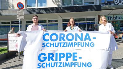 Felix Maertin,  Jutta Thoele, Sandra Dittmann halten ein Plakat mit dem Hinweis auf ihr Mühlburger Impfzentrum.