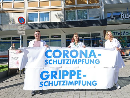 Felix Maertin,  Jutta Thoele, Sandra Dittmann halten ein Plakat mit dem Hinweis auf ihr Mühlburger Impfzentrum.
