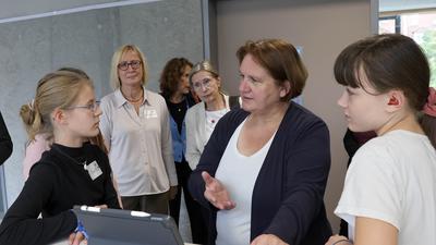 Zwei Schülerinnen erklären Kulturministerin Theresa Schopper (Mitte), wie sie an einem Ipad lernen.