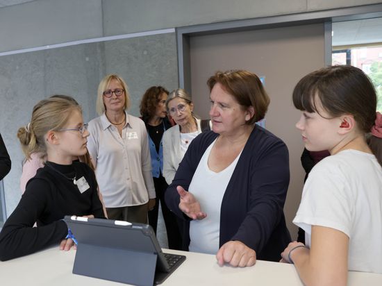 Zwei Schülerinnen erklären Kulturministerin Theresa Schopper (Mitte), wie sie an einem Ipad lernen.