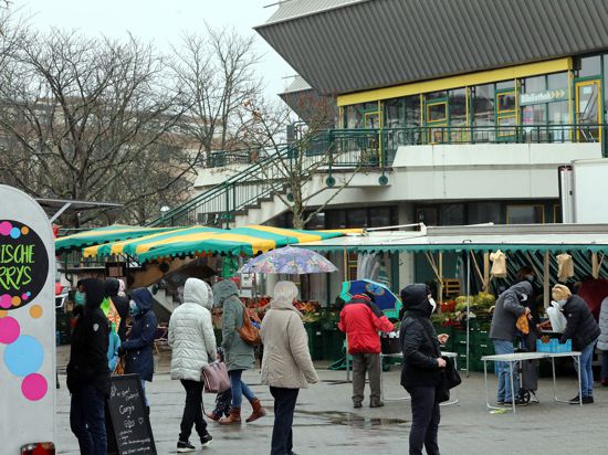 Menschen kaufen bei Regen auf dem Wochenmarkt in Neureut ein. 