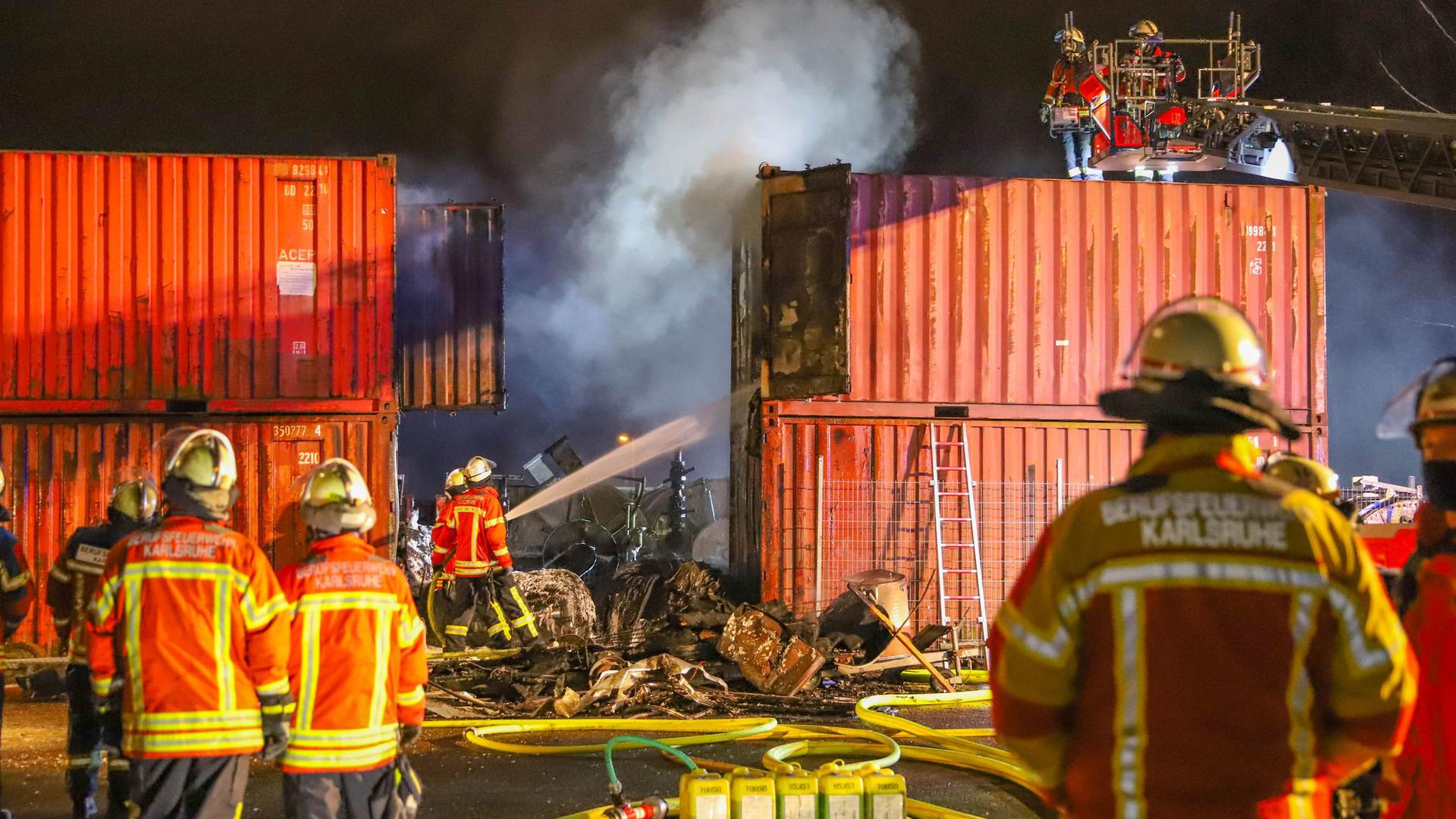 Einsatzkräfte der Feuerwehr löschen in Brand geratene Container.