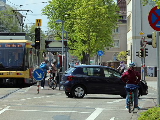 Fahrradfahrer, eine S-Bahn und ein Auto am Karl-Wilhelm-Platz in Karlsruhe.