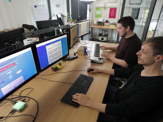 Der Elektrotechniker Sebastian Murgul (hinten) und der Informatiker Alexander Lüngen (vorne) haben ein digitales Programm mit künstlicher Intelligenz entwickelt, das zu einem Song das Notenblatt schreibt.