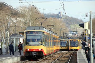 Stadtbahnen und Straßenbahnen fahren in der Durlacher Allee, im Hintergrund ragt der Turmberg auf.
