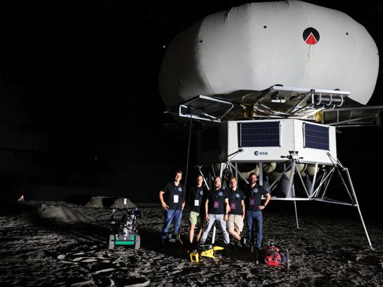 Teamfoto des FZI-Teams auf einer simulierten Mondoberfläche nebst Attrappen-Mondlandefähre.