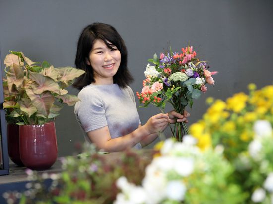 Haruka Maekawa bindet einen Strauß Blumen und achtet akribisch darauf, dass alle Farben zur Geltung kommen.