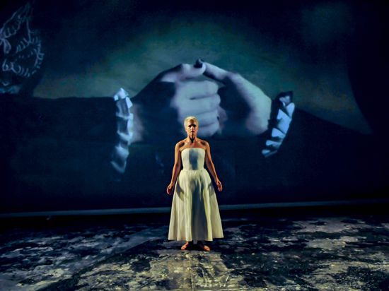 Szene aus „Romeo und Julia“ am Staatstheater Karlsruhe mit Frida Österberg als Julia vor der Projektion zweier Hände.