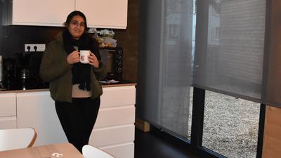 Eine junge Frau steht mit einer Kaffeetasse in der Küche ihres Tiny Houses.